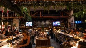 Round bar with shelves full of alcohol bottles and a flip style flight arrival board